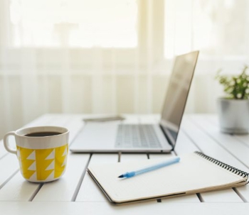 Cup of coffee, laptop and note pad