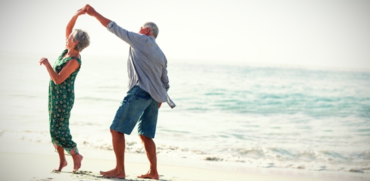 Image of two older people dancing on a beach